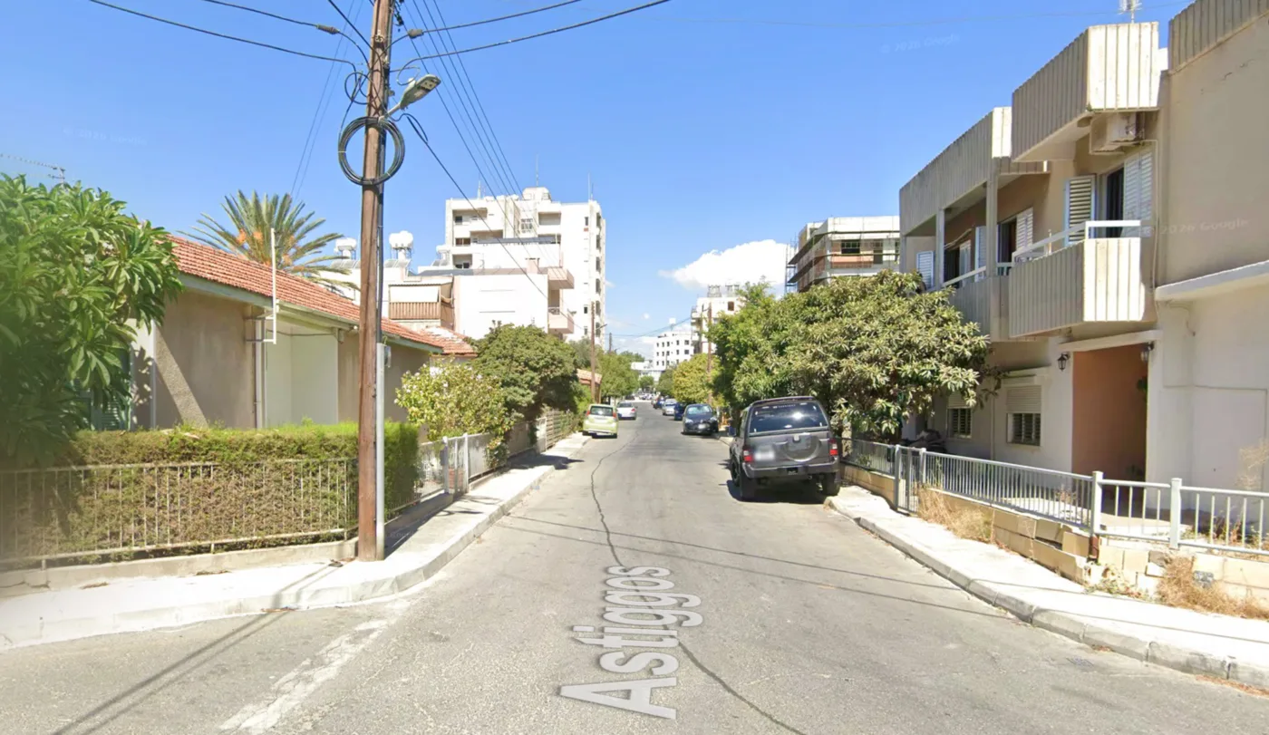 Οδός Αστυγγός: στενό οδόστρωμα, αυτοκίνητα κολλητά στη μάντρα δεξιά, το πεζοδρόμιο διακόπτεται