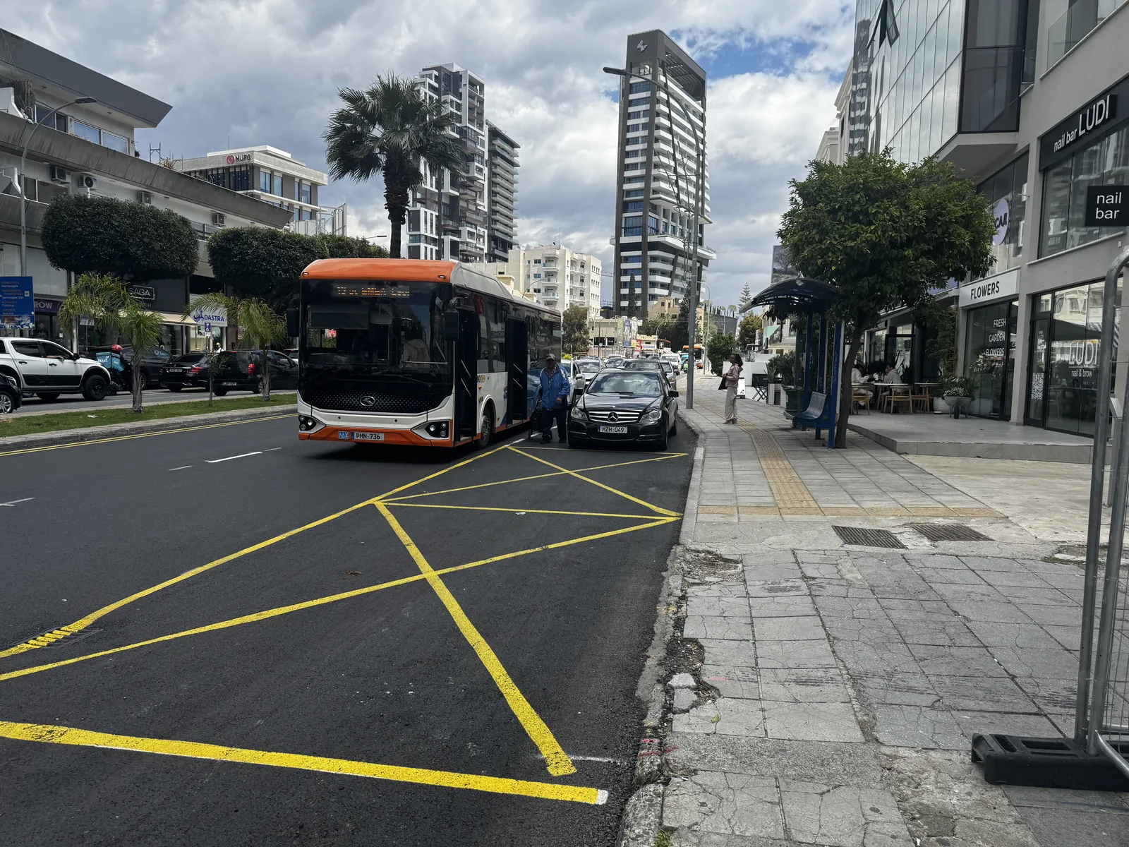 A bus bay on Limassol's coastal road: a car is parked inside the bay and the bus has stopped out in the traffic lane